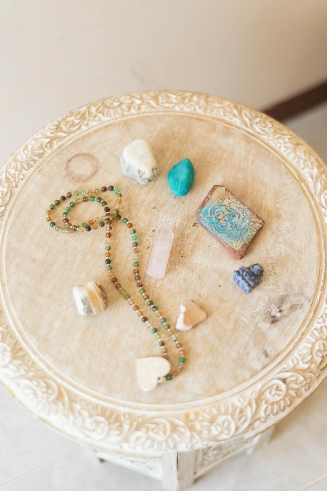 Kristalle, Mala und Amulett auf einem hellen Holztisch
