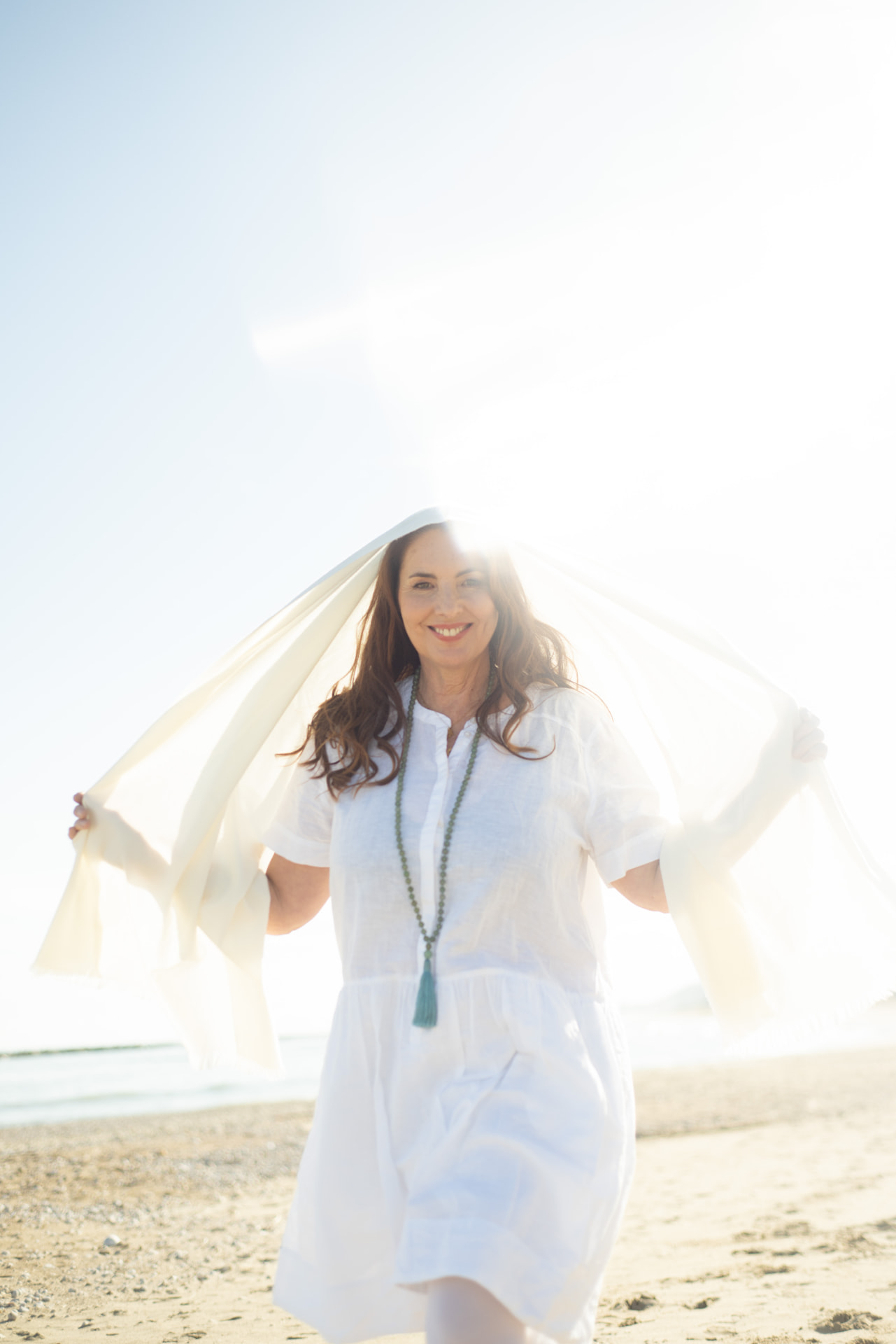 Sabine Wittmann im weissen Kleid am sonnigen Strand